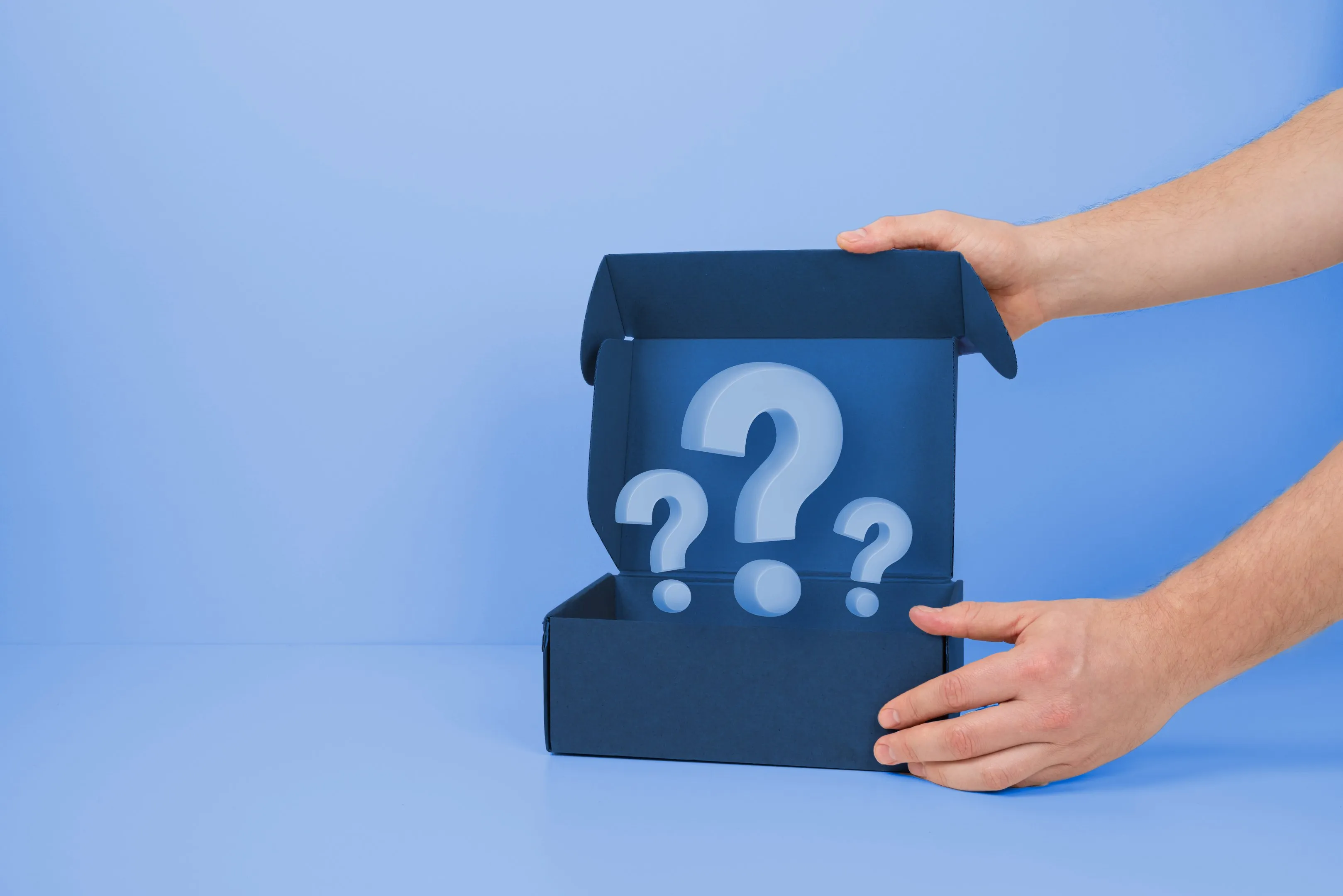 Manos abriendo una caja con signos de interrogación